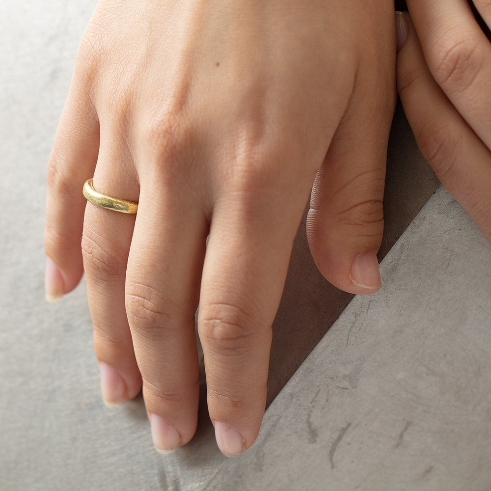 
                      
                        Narrow Molten Band in 18k yellow gold by Betsy Barron, worn on model's right hand.
                      
                    